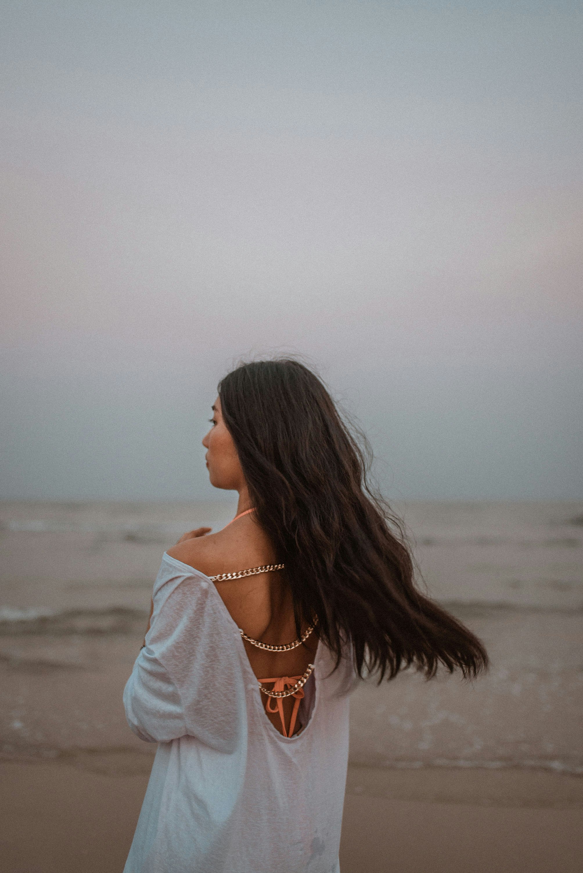 woman in white shirt standing on beach during daytime